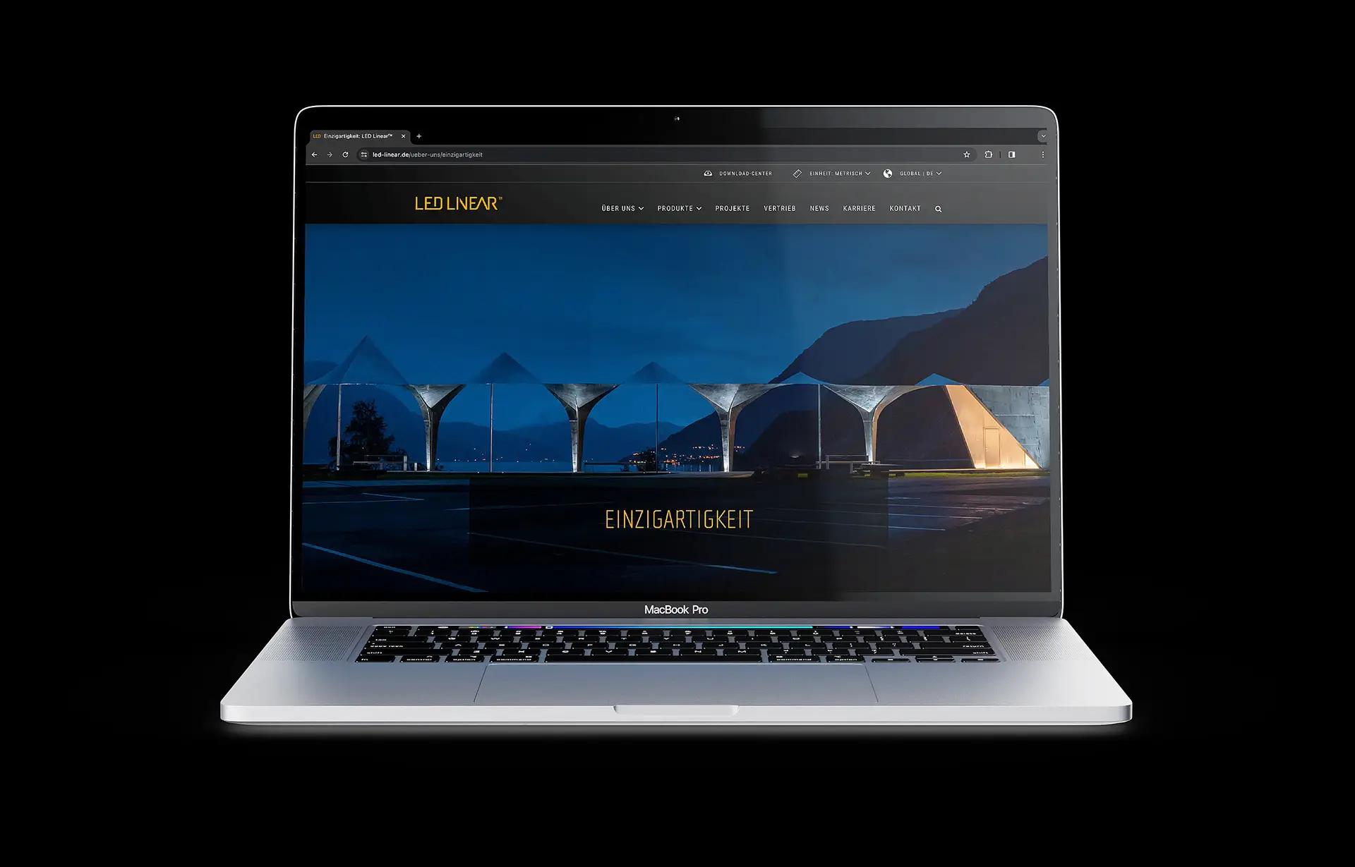 The laptop displays the LED-Linear website's home page, featuring a nighttime photo of an illuminated bridge structure and the word "Uniqueness."