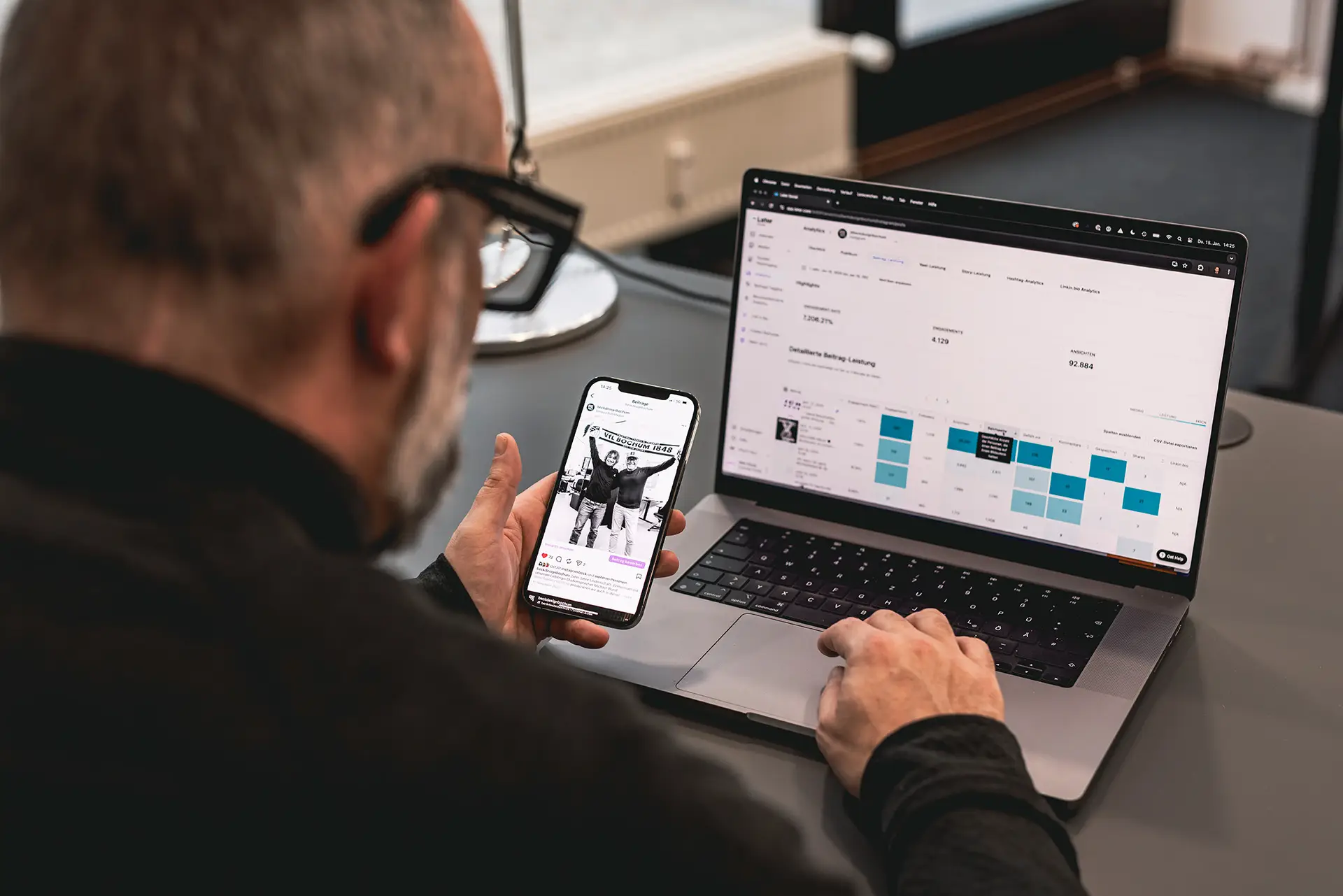 Mitarbeiter analysiert Social-Media-Kennzahlen am Laptop und vergleicht mit Instagram-Beitrag