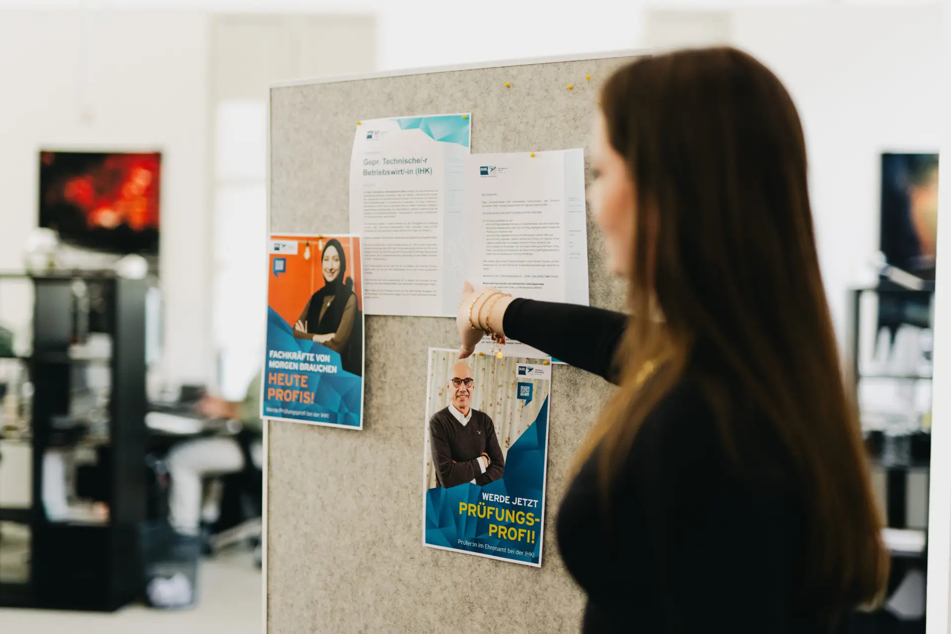Mitarbeiterin von BECKDESIGN pinnt IHK-Kampagnenplakate „Werde Prüfungsprofi" an eine Pinnwand