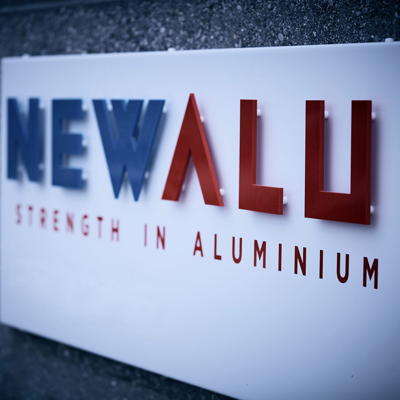 Close-up of the NEWALU logo "Strength in Aluminum," detailed view of the 3D letters